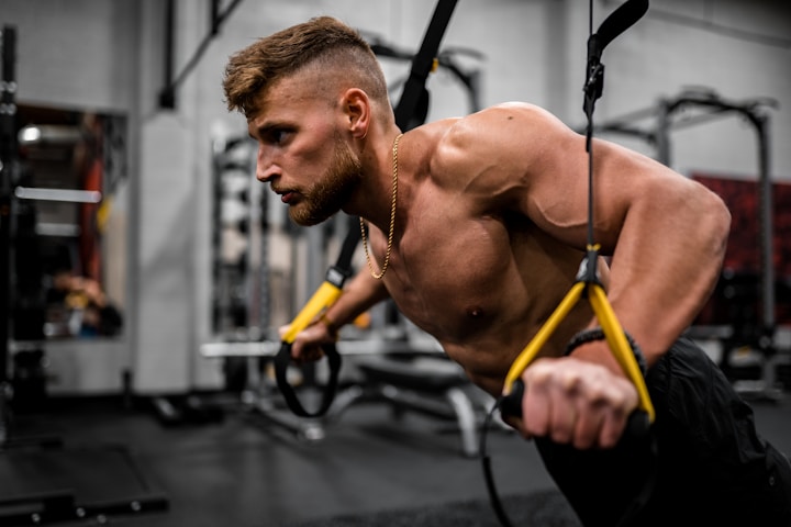 homem de topless com calças pretas segurando equipamento de exercício preto e amarelo